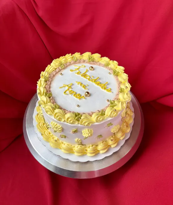 Bizcocho blanco con borde de buttercream dorado y dedicatoria escrita a mano