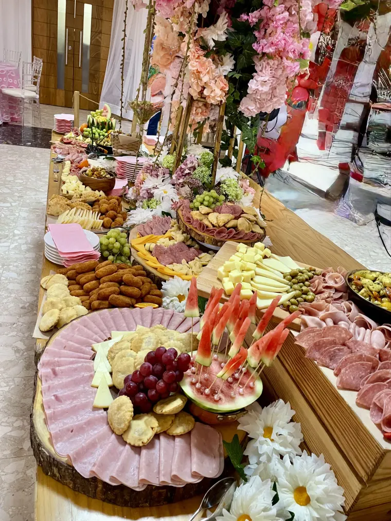 Mesa larga de grazing con fiambres, quesos, frutas y flores