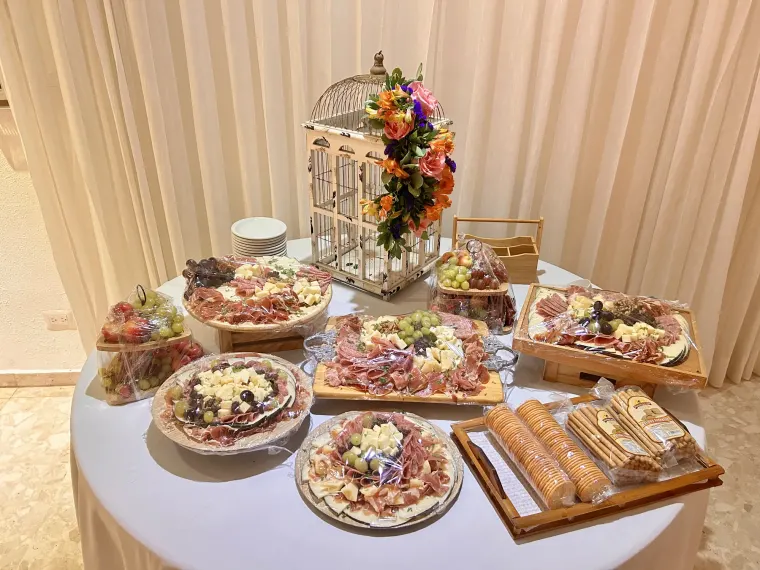 Mesa de charcutería con arreglo floral y cortinas beige