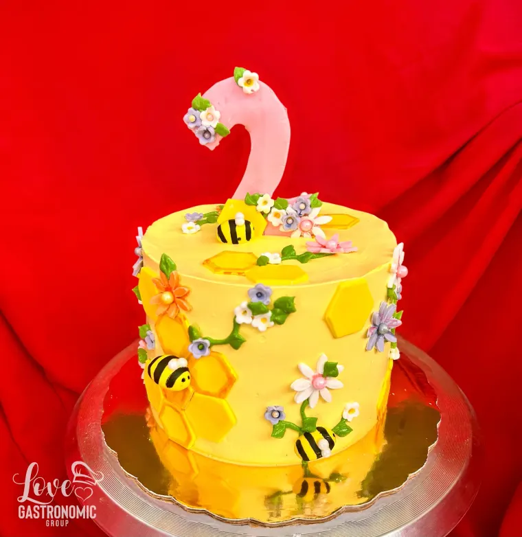 Bizcocho amarillo con abejas y flores y topper del número dos