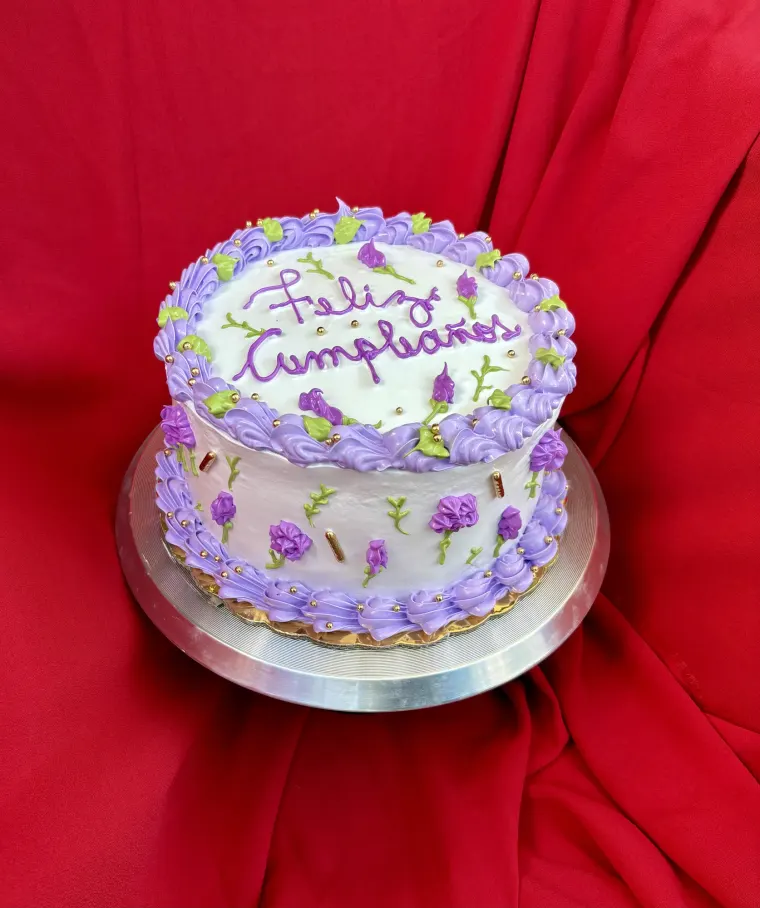 Bizcocho de dos pisos en blanco y lila con flores moradas de buttercream