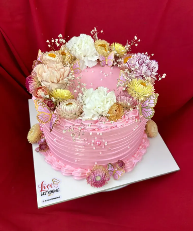 Bizcocho rosado cubierto de flores secas en tonos pastel